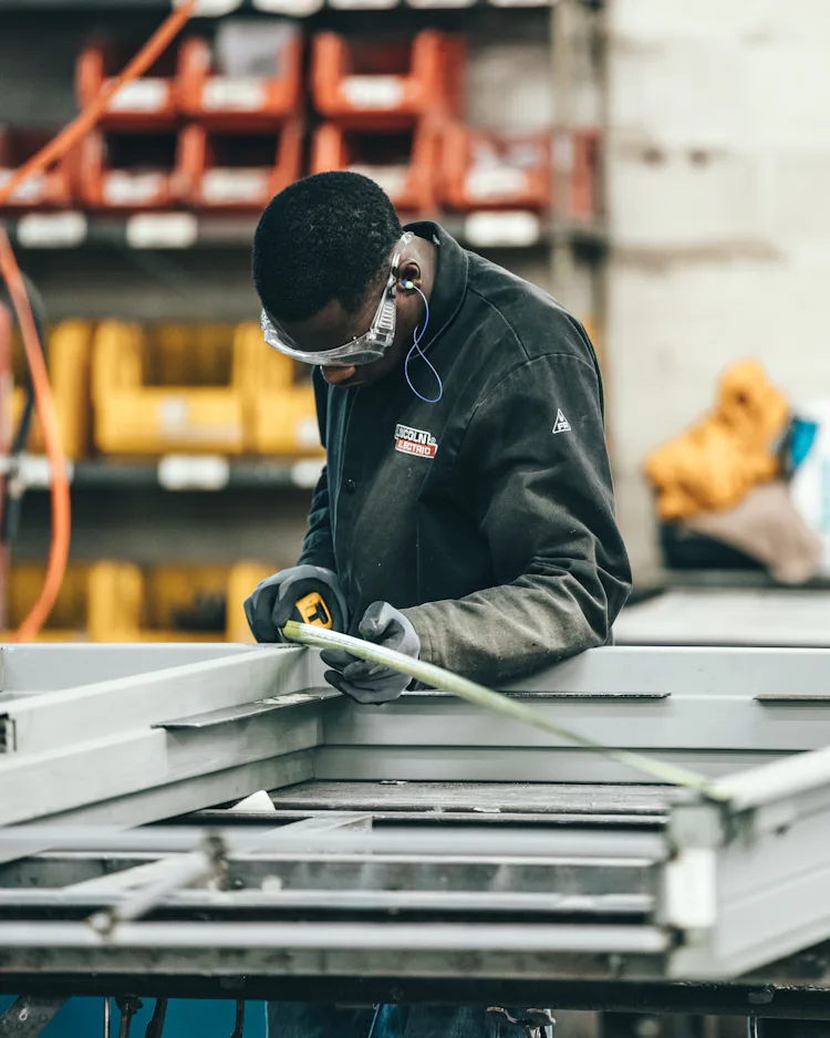 Worker measuring a metal frame in a workshop