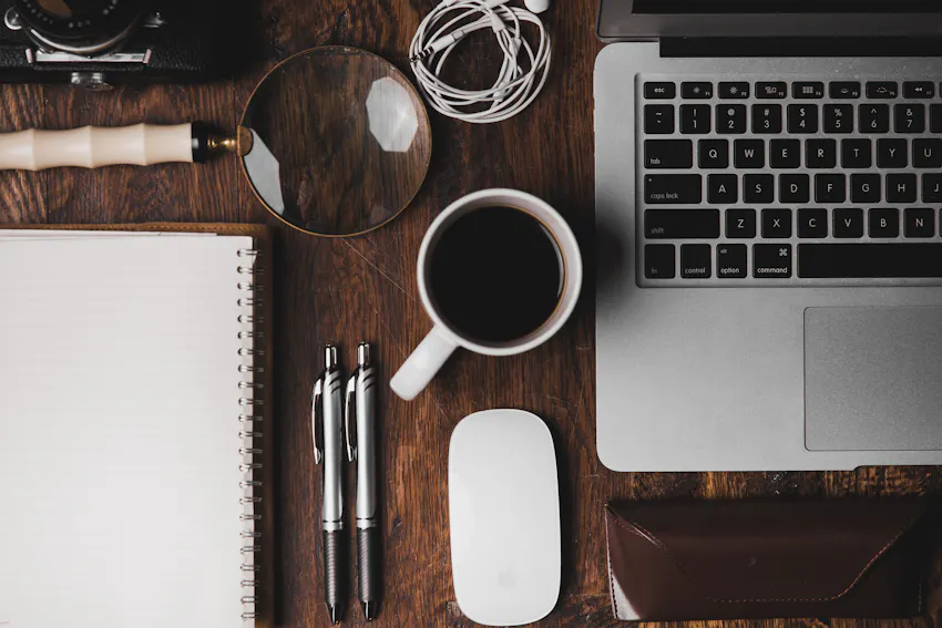 Coffee cup next to a laptop on a wooden desk